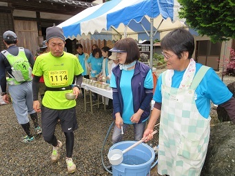 給水所で選手に水を渡す長田さん