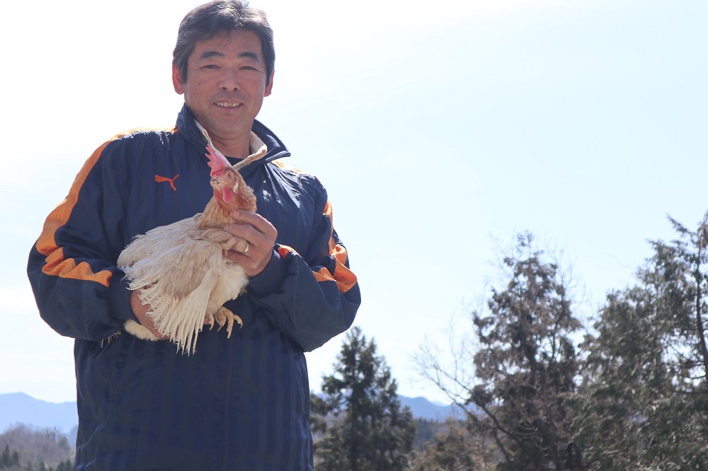 安藤鶏卵　鶏を抱えている生産者